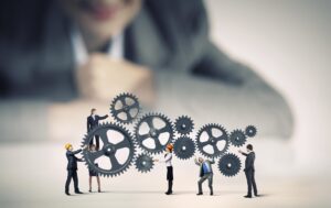 Businesswoman looking at team of businesspeople in miniature